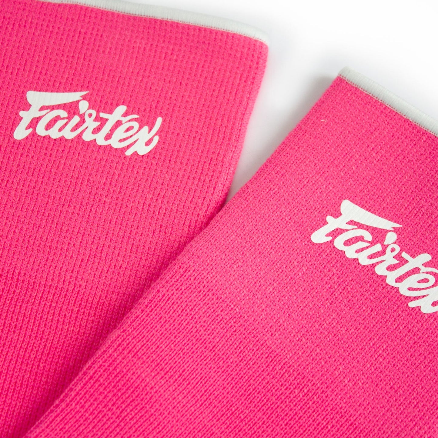 Fairtex pink and white ankle supports for sports, showing adjustable straps and cushioned padding for comfortable fit.