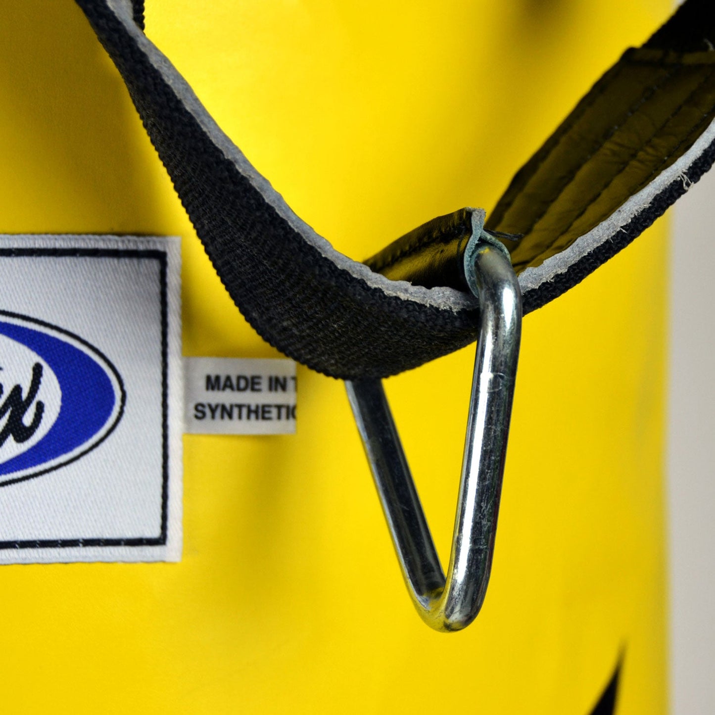 Yellow Fairtex 6ft Muaythai banana bag, unfilled, made for martial arts training, displayed hanging in a gym setting.