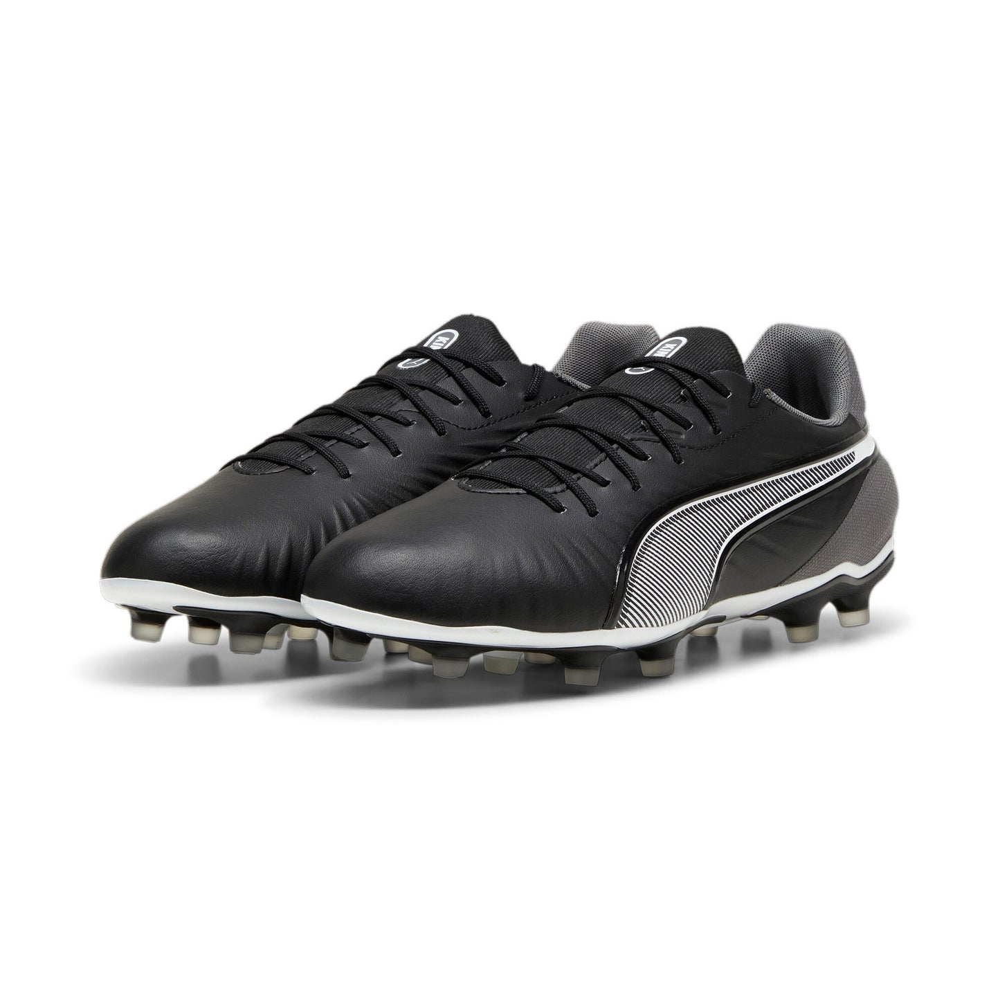 Puma King Match FG/AG football boots with black and white design, featuring studded soles for firm and artificial grass playing surfaces.