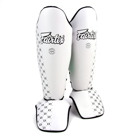 White Fairtex shin pads for martial arts training, featuring padded protection and adjustable straps for a secure fit.
